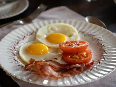 a plate of eggs and bacon on a table at KwaMbili Game Lodge in Thornybush Game Reserve