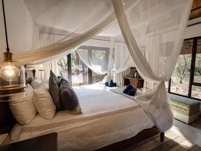 a bedroom with a white canopy bed with pillows at KwaMbili Game Lodge in Thornybush Game Reserve