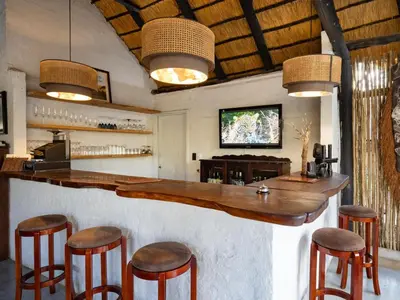 a bar in a room with some stools at KwaMbili Game Lodge in Thornybush Game Reserve