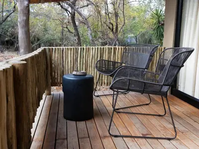 two chairs and a trash can on a deck at KwaMbili Game Lodge in Thornybush Game Reserve
