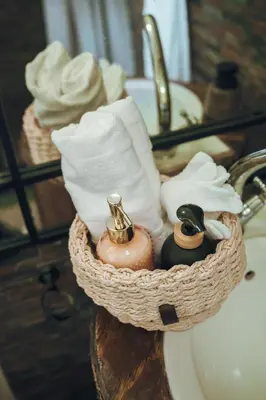 a basket of towels and toiletries on a bathroom sink at Arched Farmstead in Eerstegoud