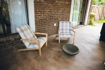 two chairs sitting on a porch next to a brick wall at Arched Farmstead in Eerstegoud