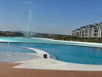 a swimming pool with a fountain in front of a building at Cosy Waterfall Midrand Apartment in Midrand