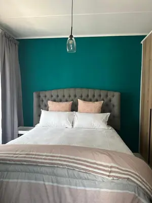 a bedroom with a large bed with a green wall at Cosy Waterfall Midrand Apartment in Midrand