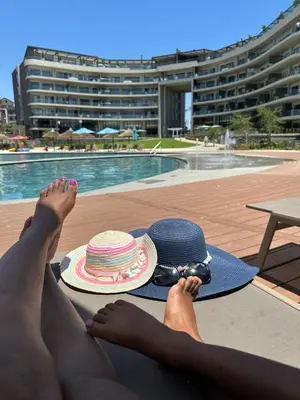 a woman laying on a towel with her feet up next to a hat at Cosy Waterfall Midrand Apartment in Midrand