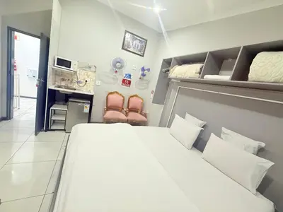 a bedroom with a large white bed and two chairs at Silent Night Guest House Sunnyside Pretoria in Pretoria