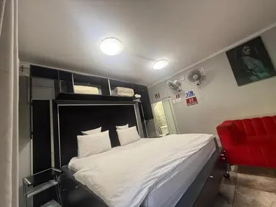 a bedroom with a large bed and a red chair at Silent Night Guest House Sunnyside Pretoria in Pretoria