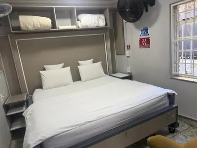 a bed with white sheets and pillows in a room at Silent Night Guest House Sunnyside Pretoria in Pretoria