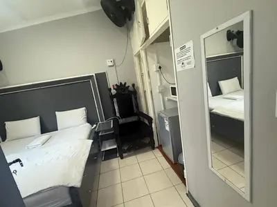a small room with two beds and a mirror at Silent Night Guest House Sunnyside Pretoria in Pretoria