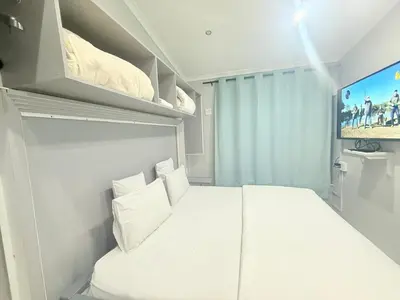 a small bedroom with a white bed and a tv at Silent Night Guest House Sunnyside Pretoria in Pretoria
