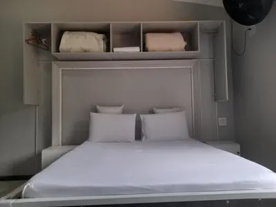 a small bedroom with a bed with white sheets and pillows at Silent Night Guest House Sunnyside Pretoria in Pretoria