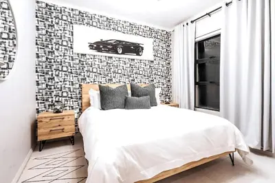a bedroom with a bed and a wall with a car picture at Midrand Classy & Eclectic 1-Bed w/Throwback Vibes in Midrand