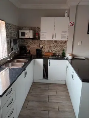 a kitchen with white cabinets and black counter tops at Edwil's Place in Hartbeespoort