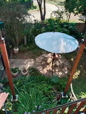 a table with a blue umbrella in a garden at Edwil's Place in Hartbeespoort