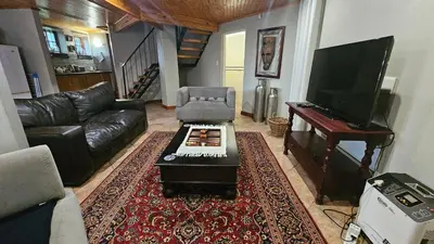 a living room with a couch and a table and a piano at Grobler's Haven Self catering cottage in Pretoria