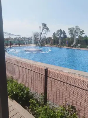 a fountain in a swimming pool with a fence at @Bevuzu Creek apartment in Pretoria