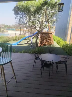 a patio with a table and chairs and a playground at @Bevuzu Creek apartment in Pretoria