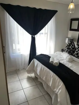 a bedroom with a bed with a black and white curtain at @Bevuzu Creek apartment in Pretoria