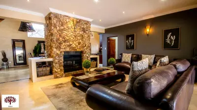 a living room with a leather couch and a stone fireplace at Zebula Golf and Wildlife Estate - The Milky Way Pax 12 - Moi Signature Luxury villa in Mabula