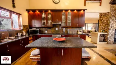 a kitchen with wooden cabinets and a granite counter top at Zebula Golf and Wildlife Estate - The Milky Way Pax 12 - Moi Signature Luxury villa in Mabula