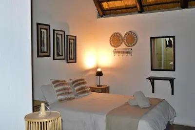 a bedroom with a white bed with pillows on it at Elijara Kruger Lodge in Marloth Park