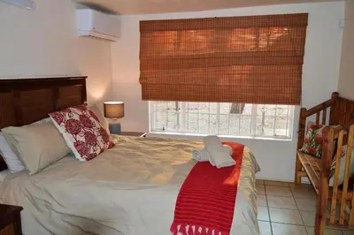 a bedroom with a bed with a red blanket on it at Elijara Kruger Lodge in Marloth Park