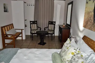 a bedroom with a bed and chairs and a table at Elijara Kruger Lodge in Marloth Park