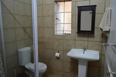 a bathroom with a toilet and a sink and a mirror at Elijara Kruger Lodge in Marloth Park