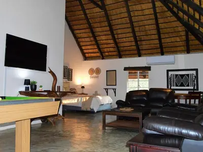a living room with leather furniture and a tv at Elijara Kruger Lodge in Marloth Park