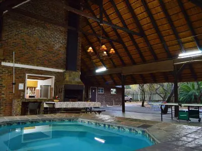 a swimming pool in a building with a pavilion at Elijara Kruger Lodge in Marloth Park
