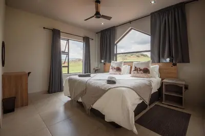 a bedroom with a large bed and a window at Highland Gate Dullstroom by Cloete's Nest in Dullstroom
