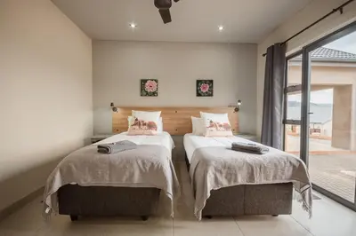 a bedroom with two beds and a large window at Highland Gate Dullstroom by Cloete's Nest in Dullstroom