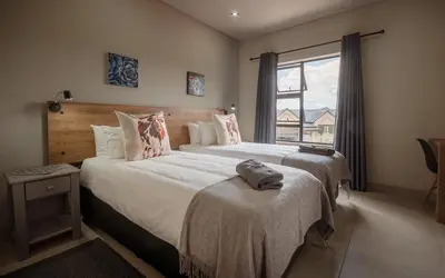 a bedroom with two beds and a window at Highland Gate Dullstroom by Cloete's Nest in Dullstroom