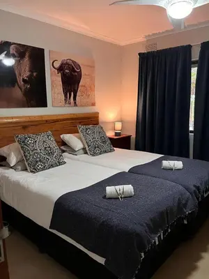 a bedroom with two beds with pillows and a picture of a bull at Blyde River Self-Catering Studios in Hoedspruit