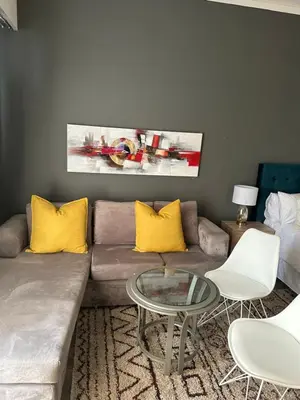 a living room with a couch with yellow pillows and a table at The Capital Trilogy Menlyn Maine Apartments 913 in Pretoria