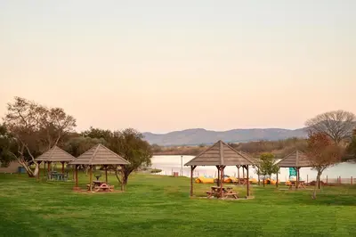 a group of picnic tables and umbrellas on a field at First Group Magalies Park in Hartbeespoort