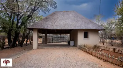 a small hut with a thatched roof and a fence at Zebula Golf and Wildlife Estate - Jackals Call Pax 8 - Moi Signature Luxury villa in Mabula