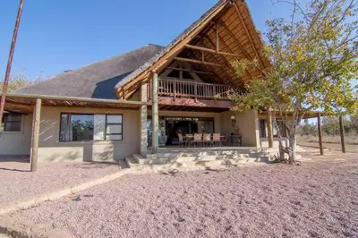 a home with a gambrel roof and a patio at Zebula Golf and Wildlife Estate - Jackals Call Pax 8 - Moi Signature Luxury villa in Mabula
