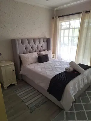 a bedroom with a large bed with a large window at Die Eend in Centurion