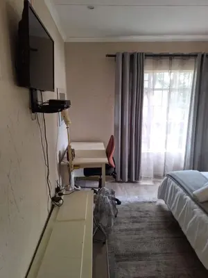a bedroom with a bed and a desk with a television at Die Eend in Centurion