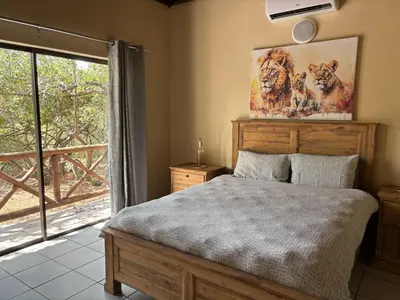 a bedroom with a bed and a large window at Le Lion Dort in Marloth Park