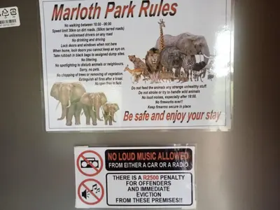 a sign on the door of a bathroom with a sign for animals at Le Lion Dort in Marloth Park