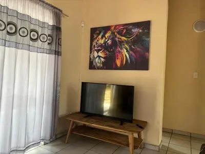 a living room with a flat screen tv next to a window at Le Lion Dort in Marloth Park