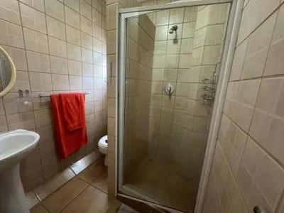 a bathroom with a shower and a toilet and a sink at Busa House in White River
