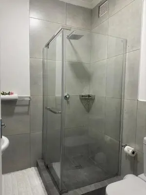 a shower with a glass door in a bathroom at Busa House in White River
