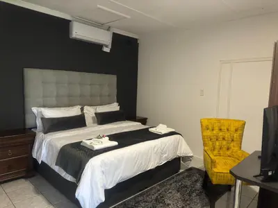 a bedroom with a bed and a chair and a television at Busa House in White River
