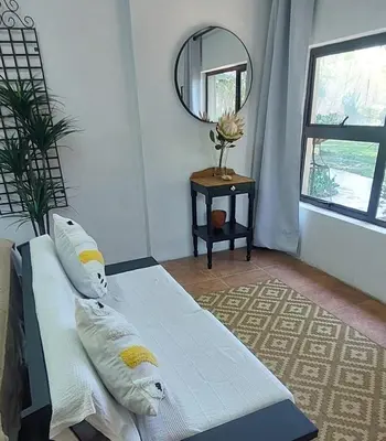 a bedroom with a bed with pillows and a mirror at Blossom Retreat at Ilnika Farm Stay in Naboomspruit