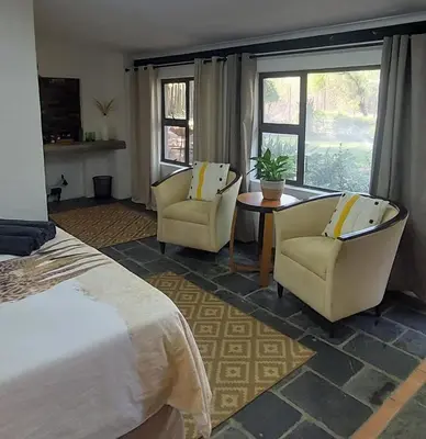 a bedroom with two chairs and a bed and a table at Ilnika Farm Stay in Naboomspruit