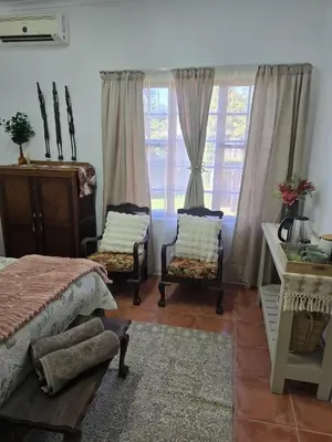 a bedroom with two chairs and a bed and a window at Ilnika Farm Stay in Naboomspruit