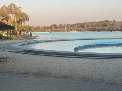 a large swimming pool next to a body of water at The Blyde Crystal Lagoon in Pretoria